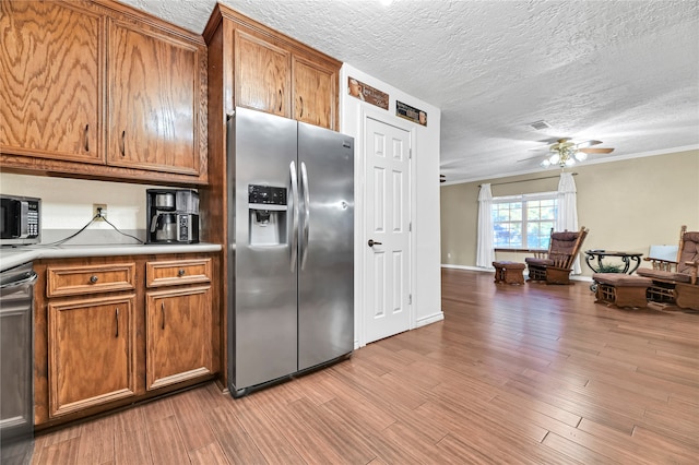 kitchen with light hardwood / wood-style flooring, a textured ceiling, stainless steel appliances, and ceiling fan