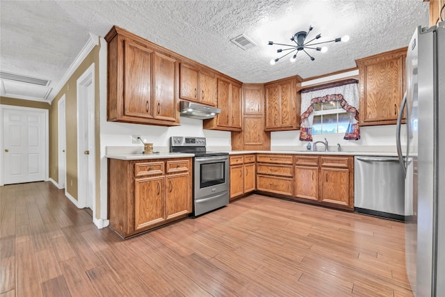 kitchen with appliances with stainless steel finishes, light hardwood / wood-style flooring, a textured ceiling, and an inviting chandelier