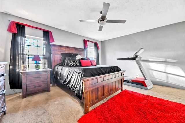 bedroom featuring a textured ceiling, light colored carpet, and ceiling fan