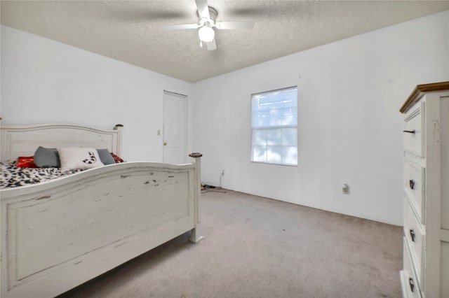 unfurnished bedroom featuring ceiling fan, light carpet, and a textured ceiling