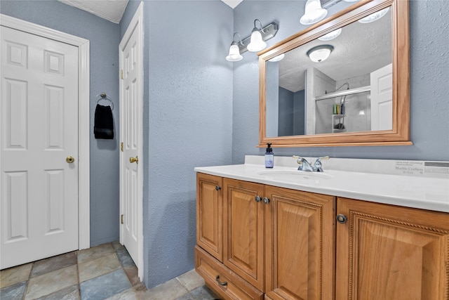 bathroom featuring vanity, a textured ceiling, and an enclosed shower