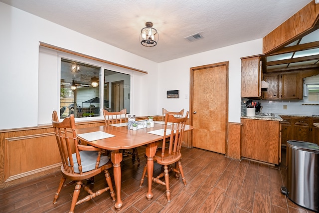 dining room featuring dark wood-type flooring, a notable chandelier, and a textured ceiling