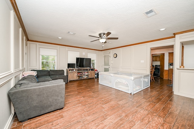 living room featuring ornamental molding, a textured ceiling, hardwood / wood-style flooring, and ceiling fan