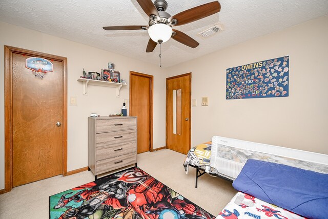 carpeted bedroom with ceiling fan and a textured ceiling