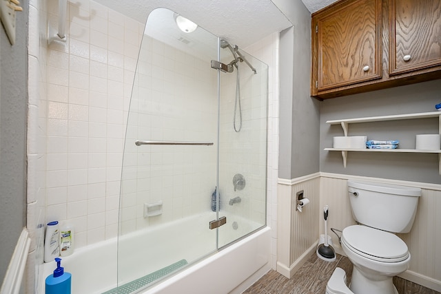 bathroom featuring toilet, a textured ceiling, shower / bath combination with glass door, and hardwood / wood-style floors