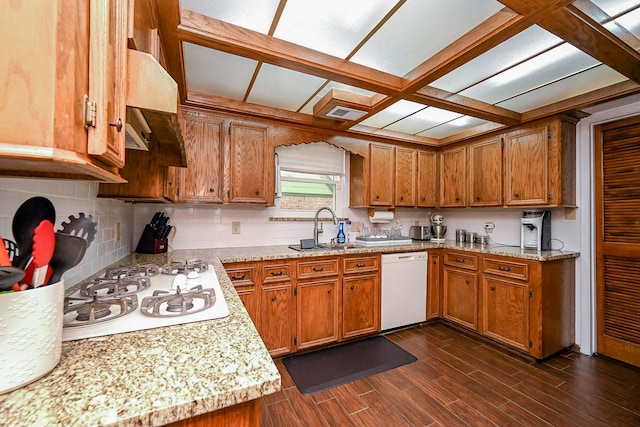 kitchen with extractor fan, dark wood-type flooring, sink, light stone counters, and white appliances