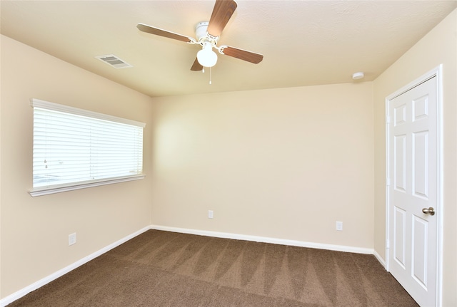 spare room featuring dark carpet and ceiling fan