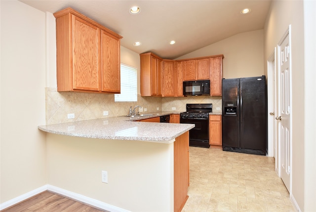 kitchen featuring kitchen peninsula, sink, black appliances, light stone countertops, and tasteful backsplash