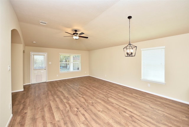 unfurnished room featuring lofted ceiling, ceiling fan with notable chandelier, and light wood-type flooring