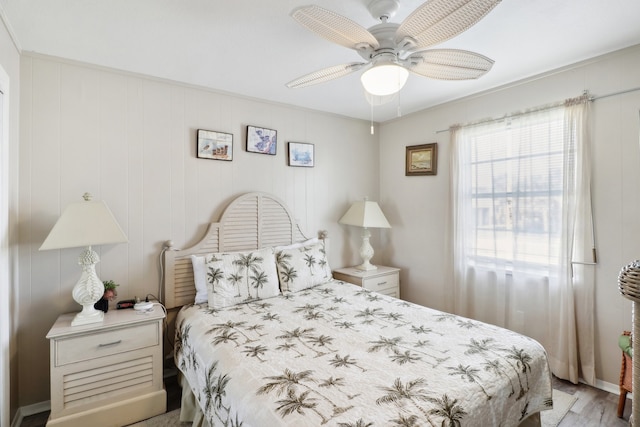 bedroom featuring wood walls, light hardwood / wood-style flooring, and ceiling fan