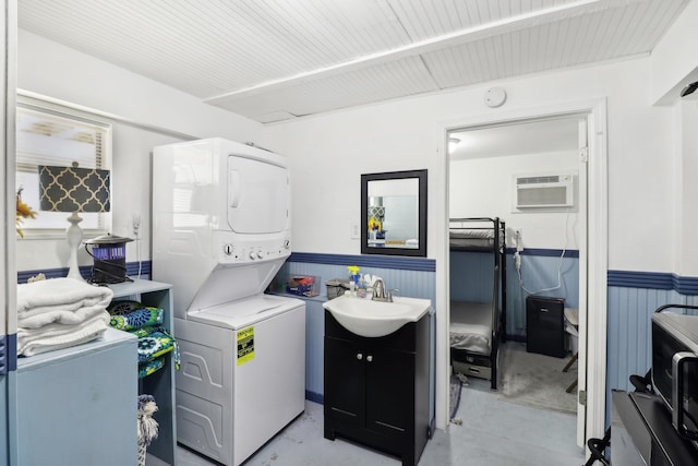 clothes washing area with a wall mounted AC, sink, and stacked washer and clothes dryer