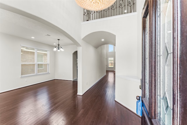 foyer entrance with a towering ceiling, dark hardwood / wood-style flooring, and an inviting chandelier