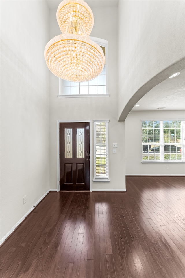 entryway featuring a chandelier, a towering ceiling, dark hardwood / wood-style flooring, and a wealth of natural light