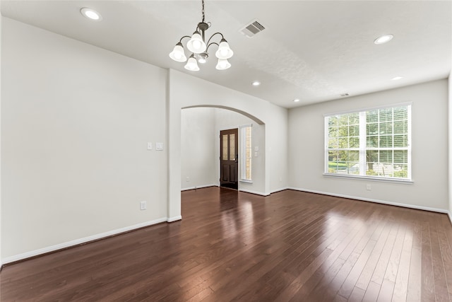 spare room featuring a chandelier and dark hardwood / wood-style flooring