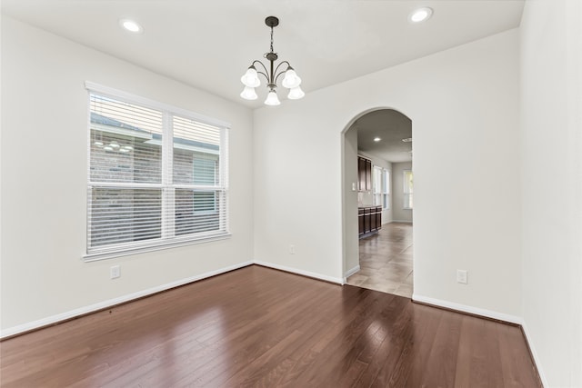 empty room with hardwood / wood-style flooring, an inviting chandelier, and plenty of natural light