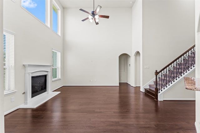 unfurnished living room with dark hardwood / wood-style flooring, a high ceiling, and a wealth of natural light