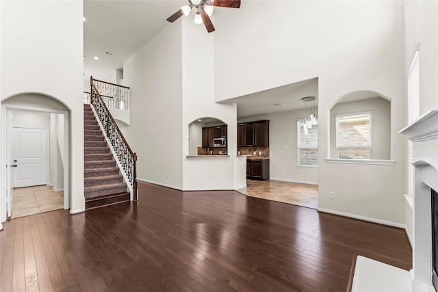 unfurnished living room featuring a high ceiling, wood-type flooring, and ceiling fan