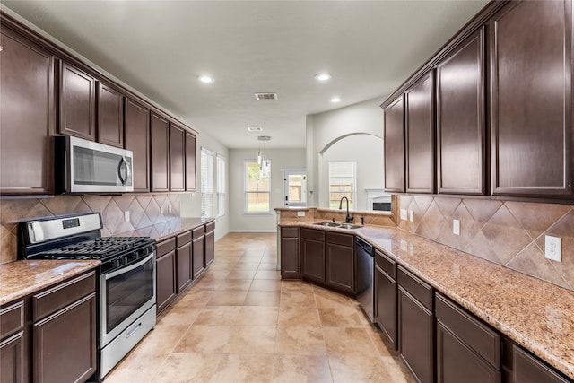 kitchen with sink, decorative backsplash, hanging light fixtures, and stainless steel appliances