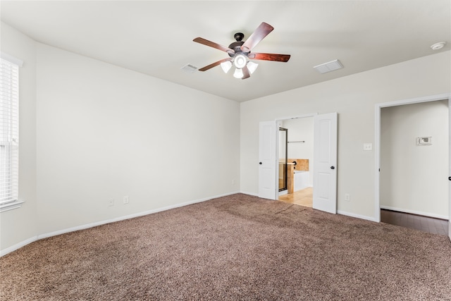 unfurnished bedroom featuring ceiling fan, light carpet, and ensuite bath