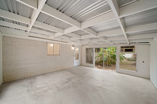 spare room with brick wall, coffered ceiling, and concrete floors