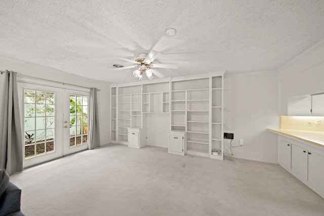 unfurnished living room featuring french doors, a textured ceiling, and light colored carpet