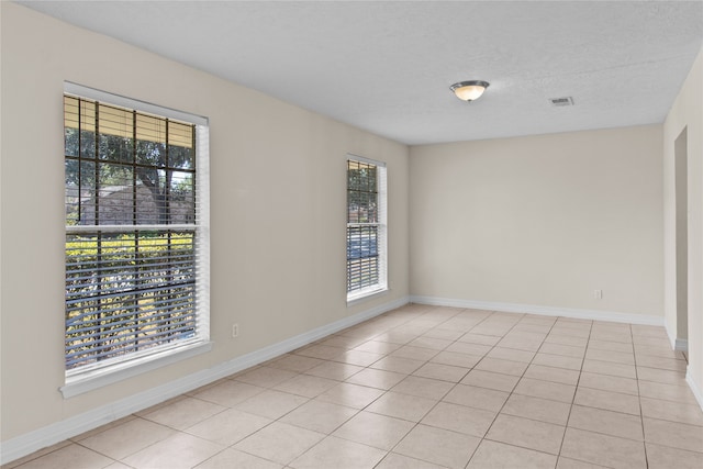 empty room with a textured ceiling and light tile patterned flooring