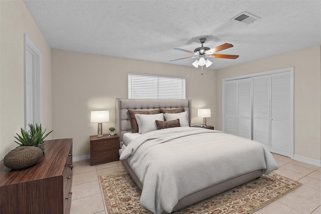 bedroom featuring a closet, ceiling fan, a textured ceiling, and light tile patterned floors