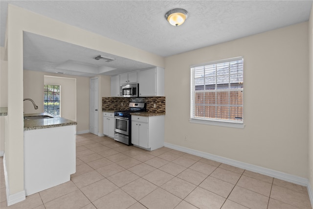 kitchen with sink, appliances with stainless steel finishes, white cabinetry, and plenty of natural light