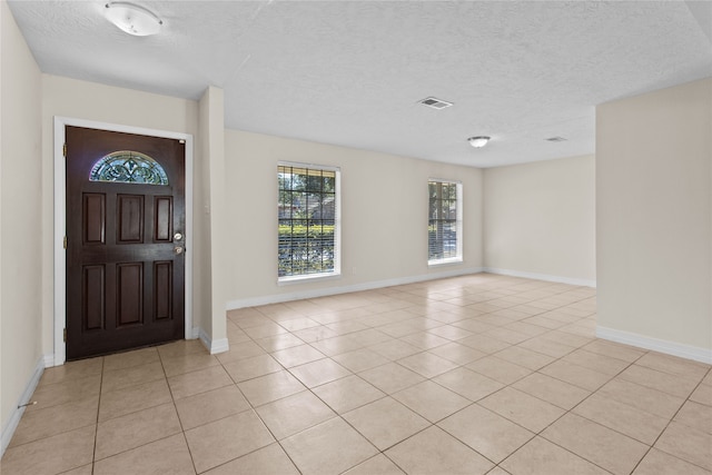 entrance foyer with a textured ceiling and light tile patterned floors