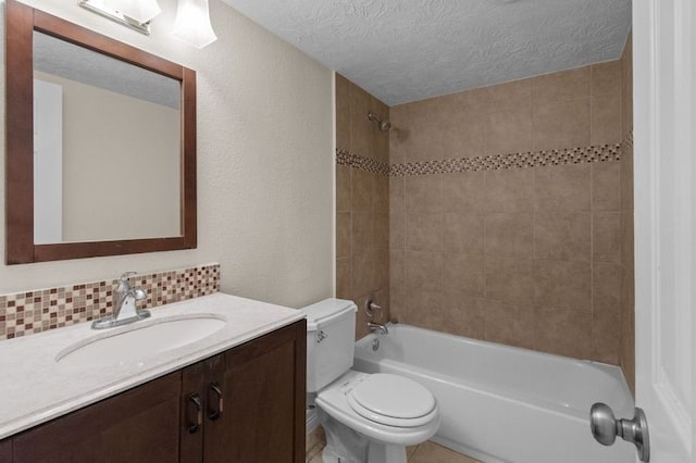 full bathroom featuring vanity, toilet, a textured ceiling, and tiled shower / bath