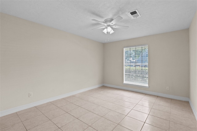 spare room featuring a textured ceiling, ceiling fan, and light tile patterned floors