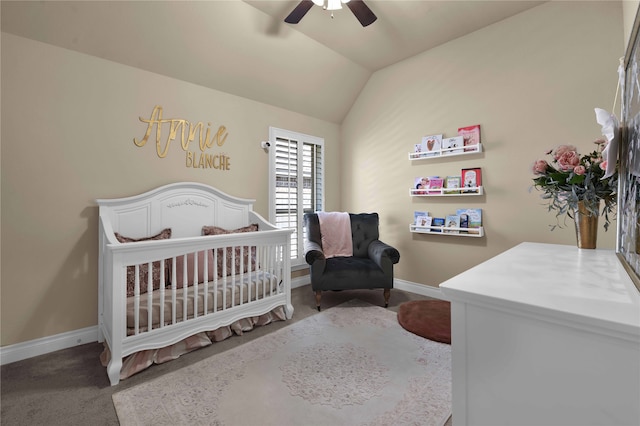 carpeted bedroom with a crib, vaulted ceiling, and ceiling fan