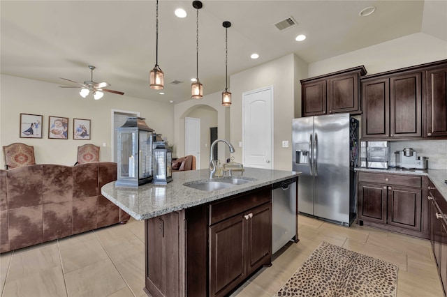 kitchen with appliances with stainless steel finishes, sink, an island with sink, backsplash, and pendant lighting