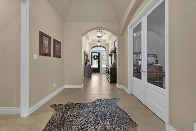 hall featuring french doors, light tile patterned flooring, and vaulted ceiling