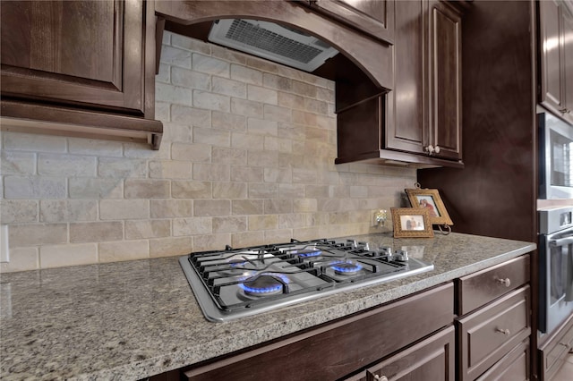 kitchen featuring dark brown cabinets, stainless steel appliances, and backsplash