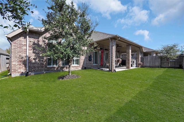 rear view of property with a patio area, a yard, and ceiling fan