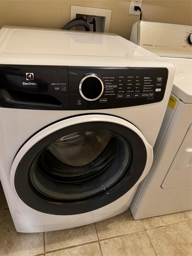 washroom with washing machine and dryer and light tile patterned floors