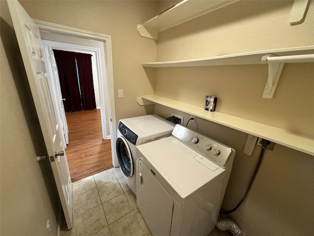 laundry area with washing machine and dryer and light wood-type flooring