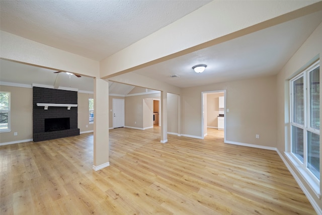 unfurnished living room with light hardwood / wood-style flooring, a textured ceiling, and a fireplace