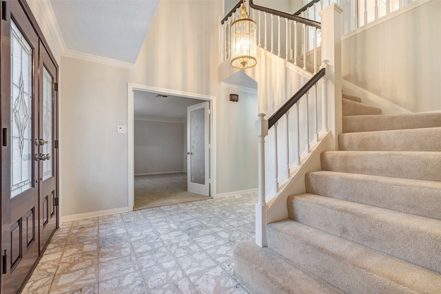 entrance foyer with an inviting chandelier, ornamental molding, french doors, and a towering ceiling