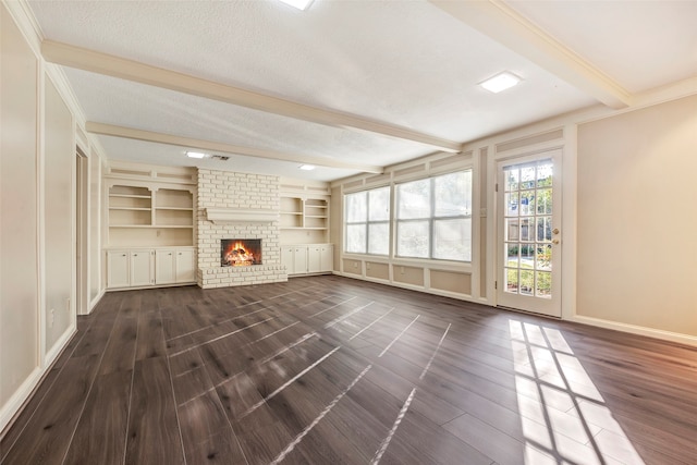 unfurnished living room featuring a textured ceiling, a brick fireplace, ornamental molding, dark hardwood / wood-style floors, and beamed ceiling