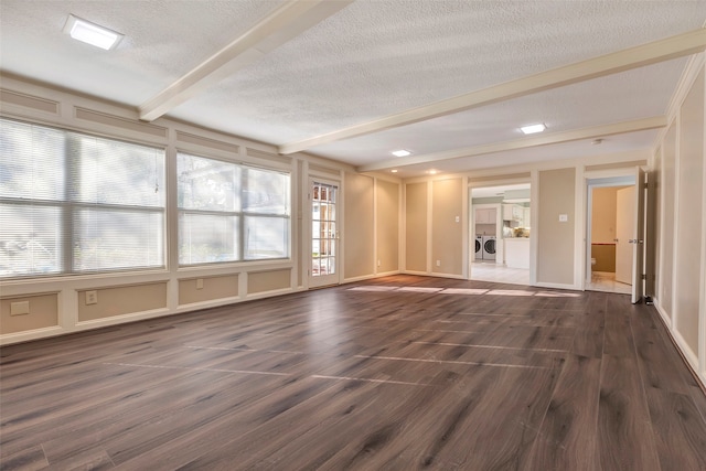 unfurnished living room with dark wood-type flooring, independent washer and dryer, beamed ceiling, and a textured ceiling