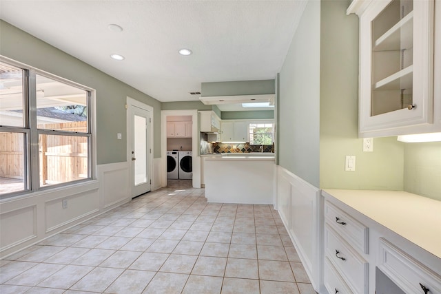 kitchen featuring white cabinetry, tasteful backsplash, light tile patterned flooring, and washing machine and clothes dryer