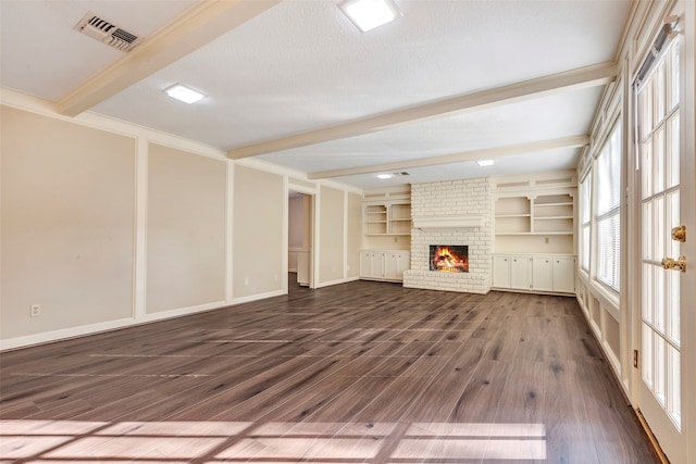 unfurnished living room with dark hardwood / wood-style floors, beam ceiling, a brick fireplace, a textured ceiling, and built in shelves