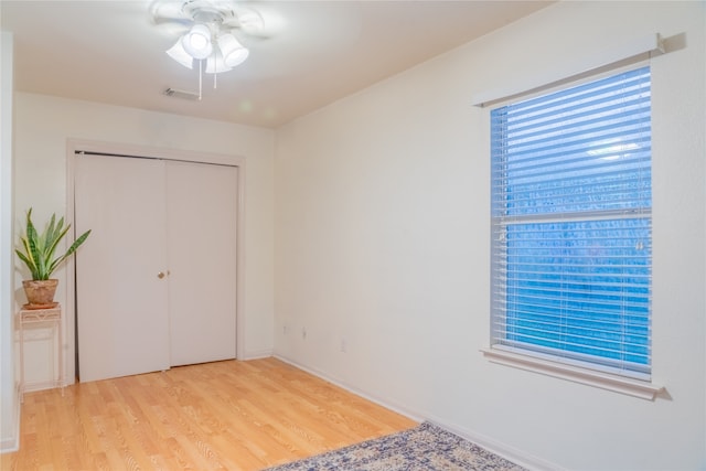 unfurnished bedroom with light hardwood / wood-style floors, ceiling fan, and a closet