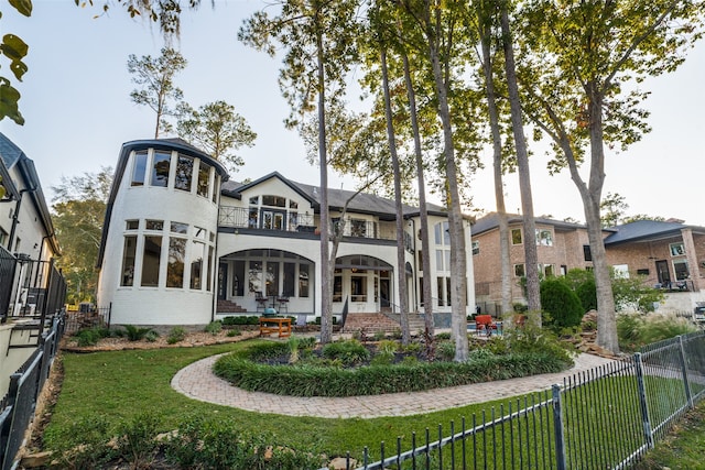 rear view of house with a balcony and a yard