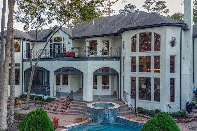 back of house with an in ground hot tub, a patio area, and a balcony