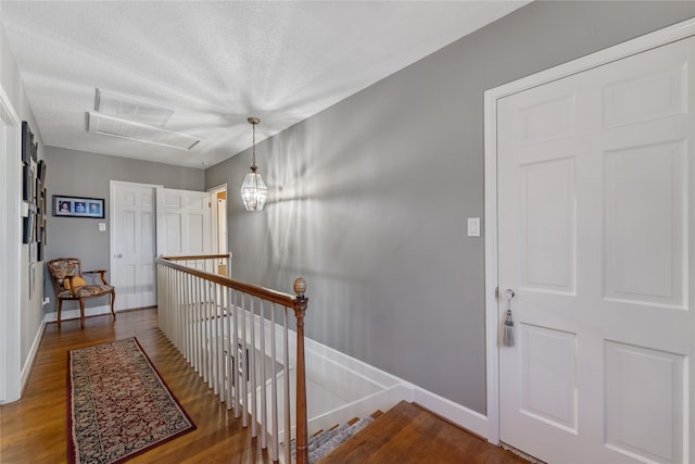 hallway featuring a textured ceiling, dark hardwood / wood-style floors, and a notable chandelier