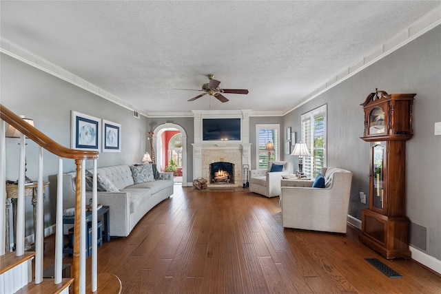 living room with ceiling fan, crown molding, dark wood-type flooring, and a textured ceiling