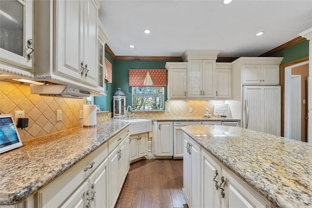 kitchen with glass insert cabinets, paneled appliances, ornamental molding, and a sink